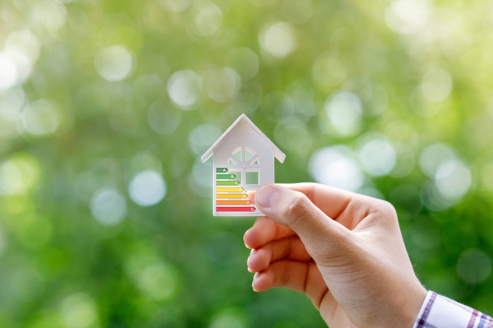 ersoon houdt een modelhuis vast met een energie-efficiëntielabel, als illustratie van EPB-wetgeving en het belang van lage U-waarden