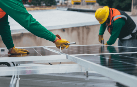 Monteurs installeren zonnepanelen op een plat dak.