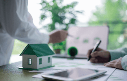Adviseurs bespreken energieprestaties met woningmodel op tafel.